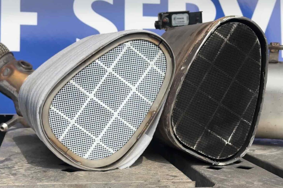 Neue weiße DPF-Wabe neben der alten schwarzen, beschädigten Wabe eines Volvo XC40 vor dem FixBox-Schild